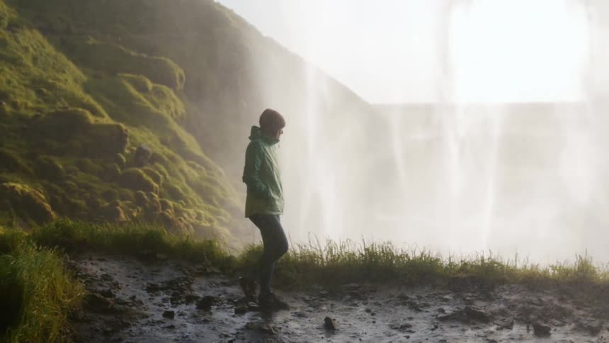 A person walks behind a waterfall in the wilderness