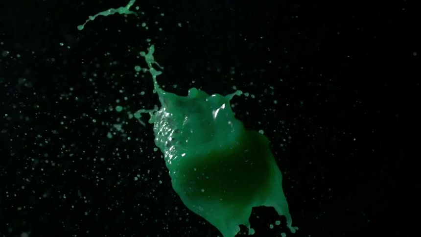 Dart being thrown at balloon then green liquid pouring out in slow motion