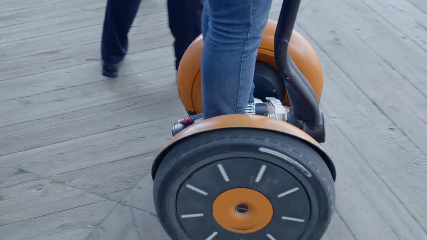 Close of a segway being ridden by a person a wooden board walk