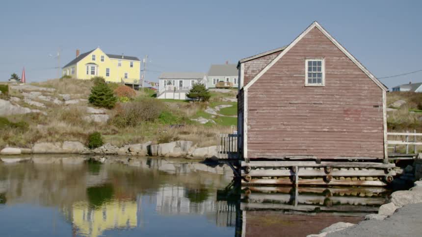 A hut built next to a pier on a pond with houses in the background