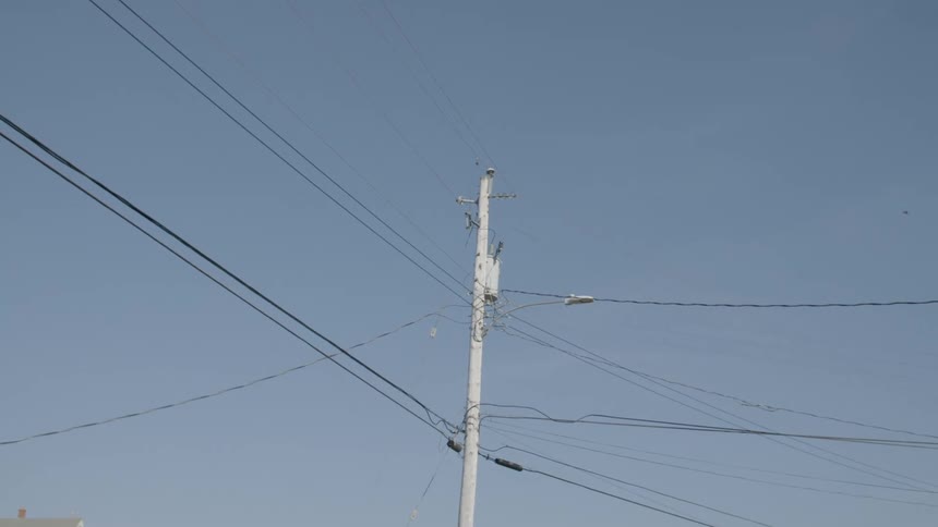 A utility pole with electrical power lines and the sky in the background