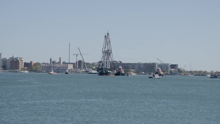 Birds fly over boats floating near buildings on shore