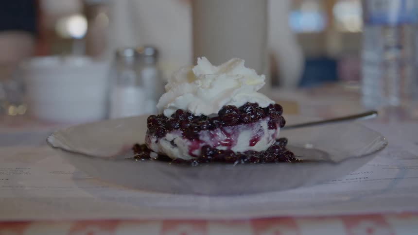 Blueberry cheesecake dessert with whipped cream on a clear glass plate