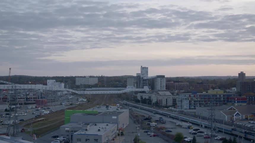 A neighborhood with buildings streets and parking lots with the sky in the background