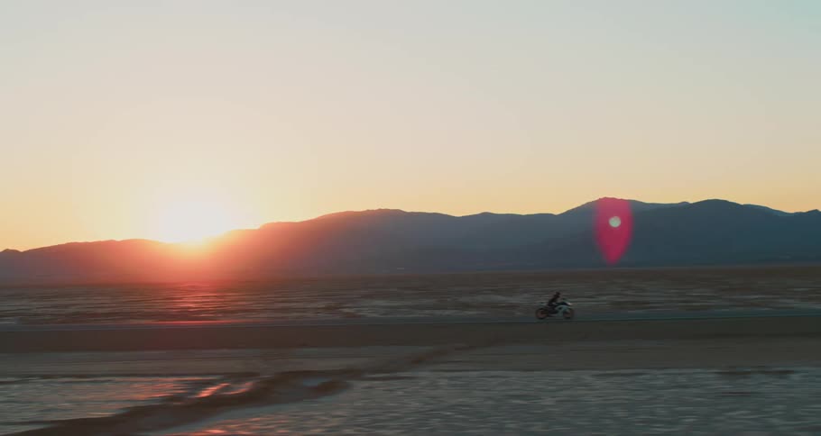 A person drives a motorcycle across a desert