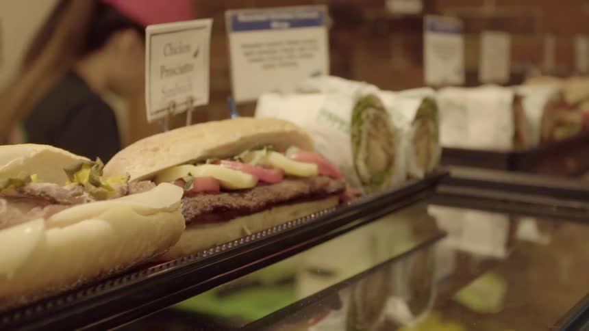 Trays of sandwiches line the top of a counter in a restaurant