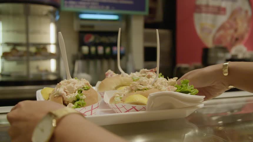 A woman picks up a tray of sandwiches off of a counter