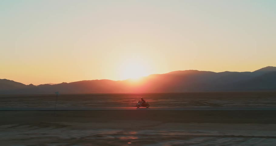 A motorcycle travels over a road through a desert