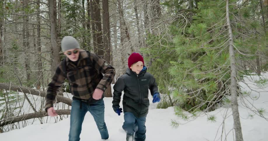 Father and son walk in the snow covered woods