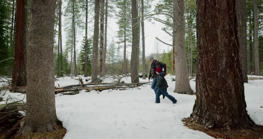 A father and son hike through a snow covered forest