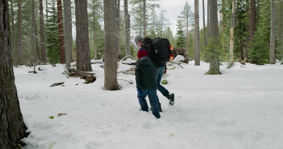 Two people hike in the snow of the forest