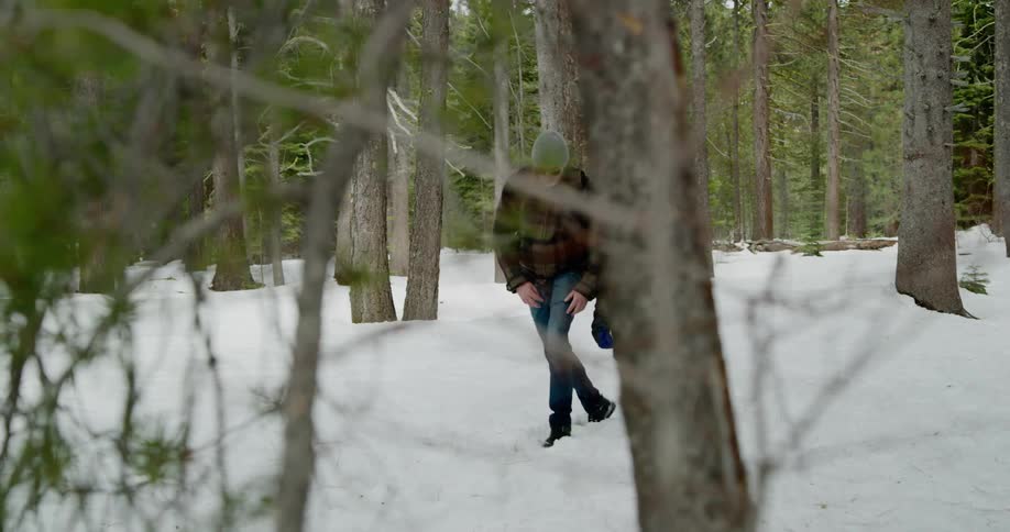 Father and son walk through the snow in a wooded area while talking with one another