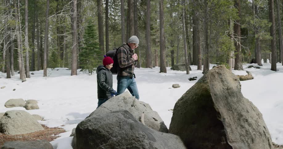 Father and son walk on the snow near a forest at day