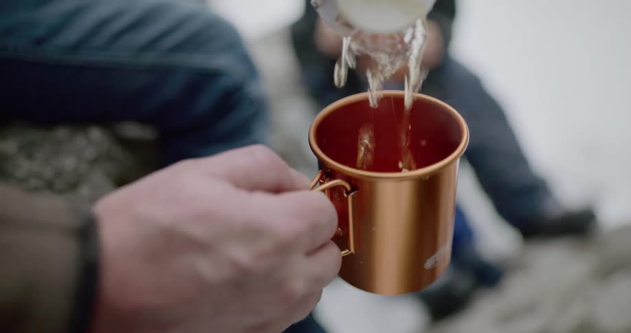A man pours a hot drink in to a mug
