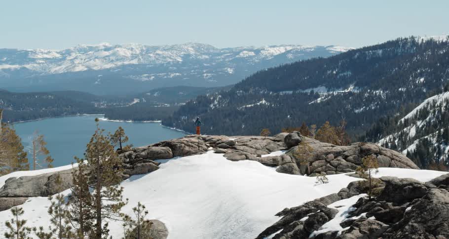 A person climbs to the top of a mountain to take in the view