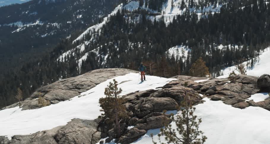 A person stands at the top of a mountain on skis