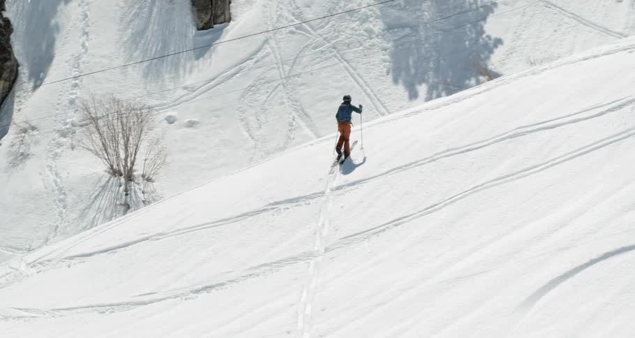 A person climbs up the slope with skis