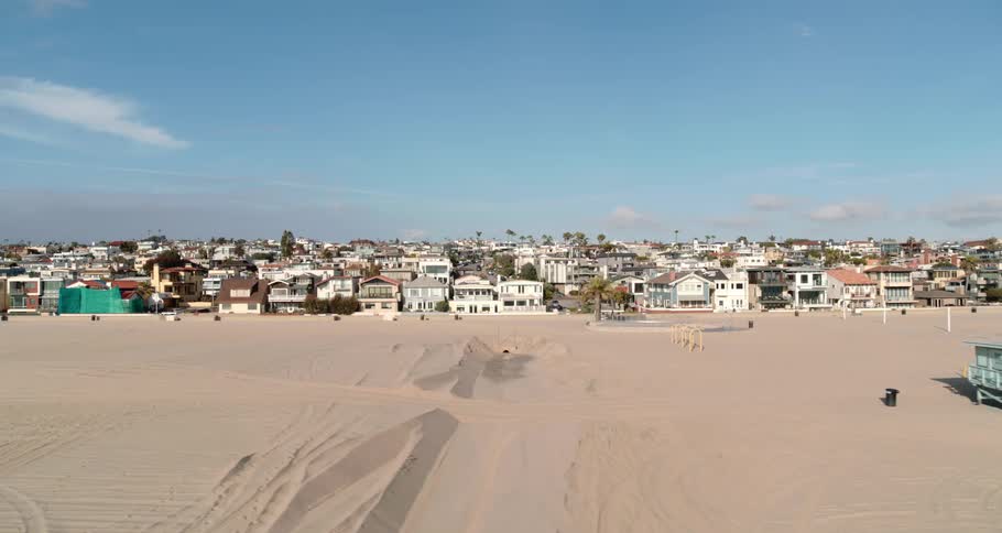 A beach with sand with houses in the background
