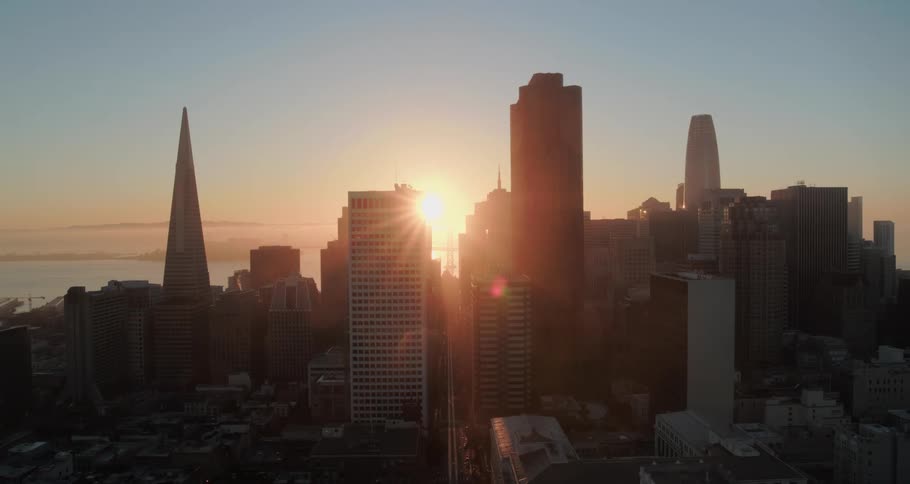 Aerial view of a city with a body of water far in the distance at dawn or dusk