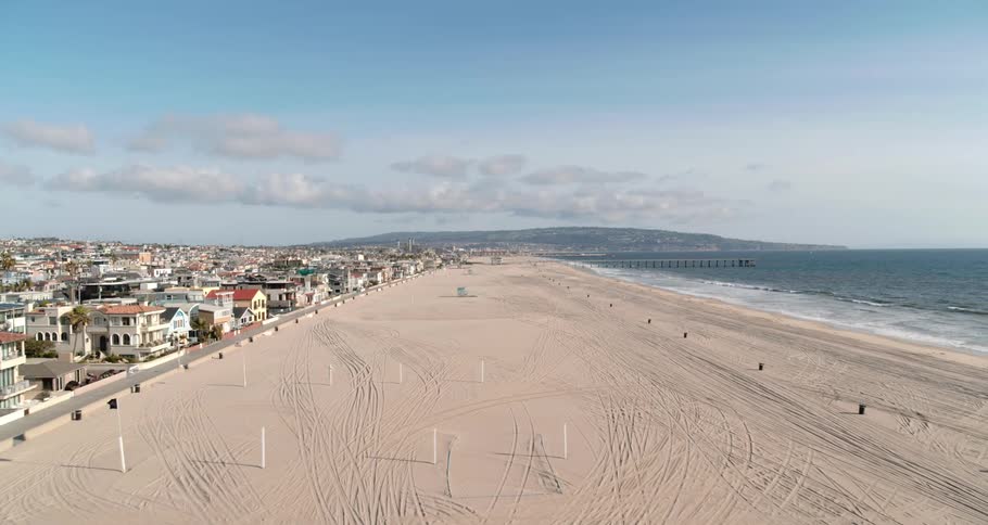 A spacious beach sits empty in front of a dense neighborhood