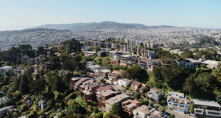Homes and roads on a hilltop neighborhood overlooking the valley and hills on the horizon