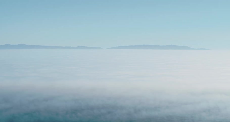 Clouds cover the sky except for the tops of distant mountains