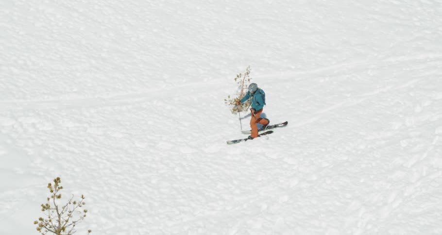 A person walks in full ski gear through a snow terrain