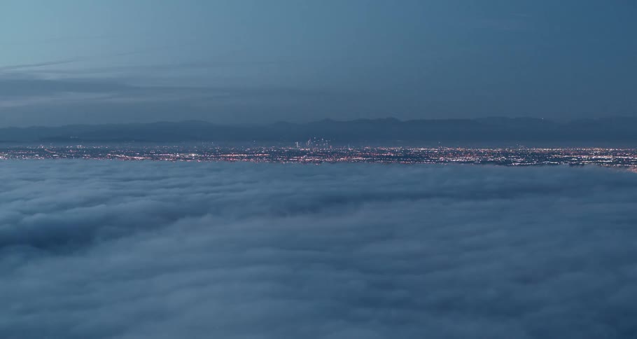 Aerial view of city covered by clouds at sunset