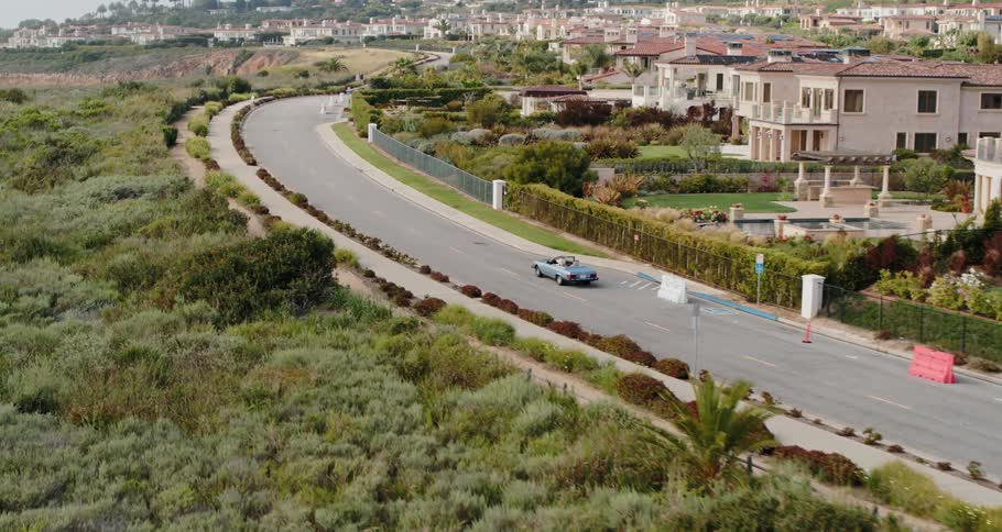 A vehicle travels a road next to a large neighborhood