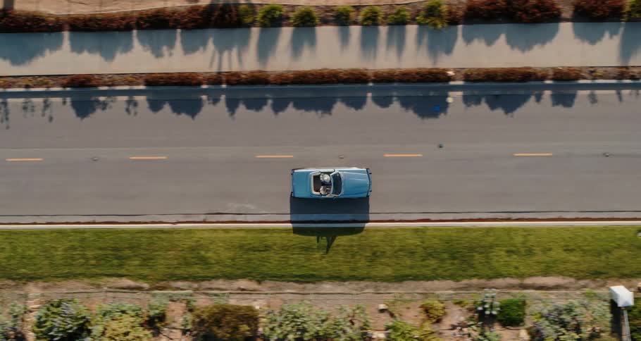 A blue car drives down a road