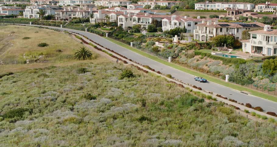 A car drives down a street in front of a neighborhood