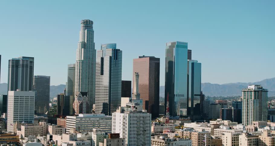 Several skyscrapers rise from the downtown area of a city near some hills