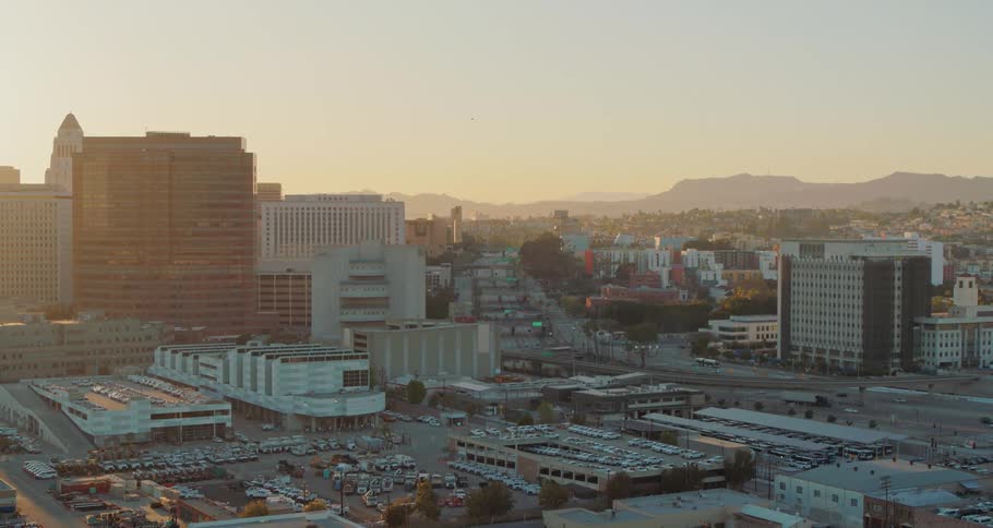 Cars and trucks travel on a highway past buildings and parking lots and garages