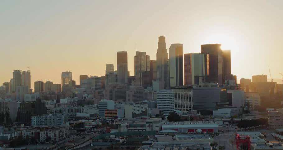 The sun peeks out from behind a large city skyline