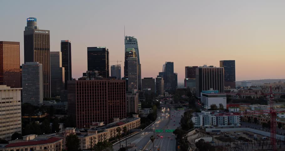 Aerial view of the city skyline and vehicles driving along the roads at dusk