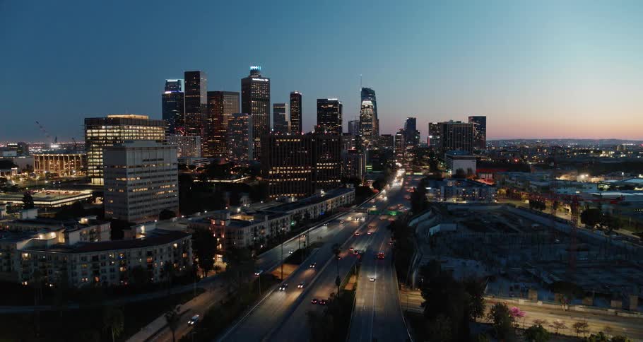Aerial view of the illuminated high rise buildings and vehicles moving along the roads
