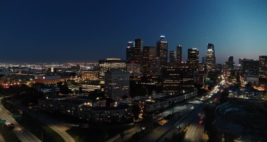 Aerial view of the illuminated high rise buildings and vehicles moving along the roads at night