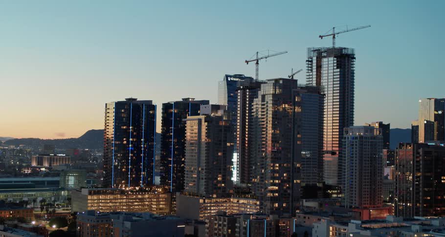 A city skyline with buildings cranes and the sky in the background
