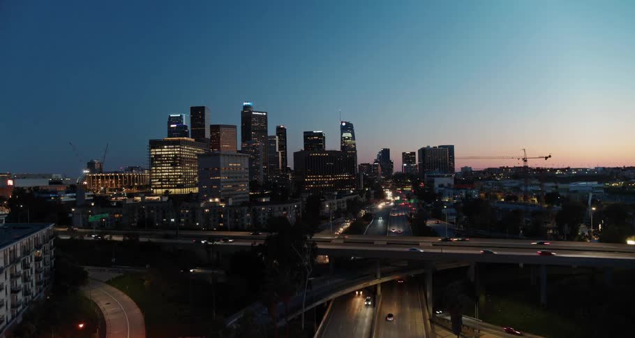 Aerial view of city skyline and vehicles moving along roads at dusk