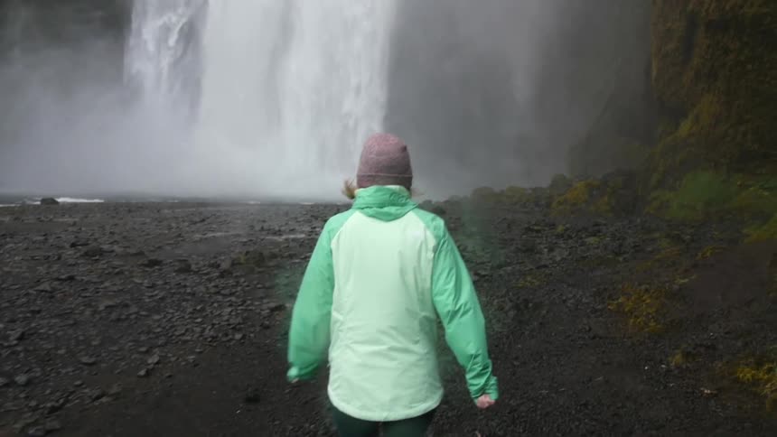 A woman runs over to the side of a waterfall