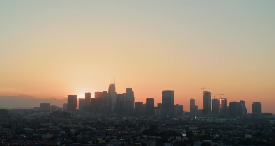 The sun is nearly set behind the buildings in the distance