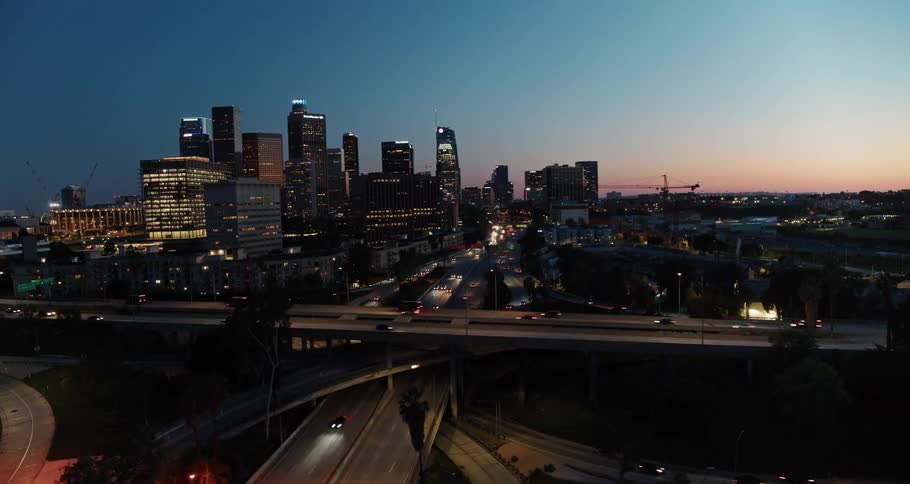 Aerial view of city skyline and vehicles moving along the roads at dusk