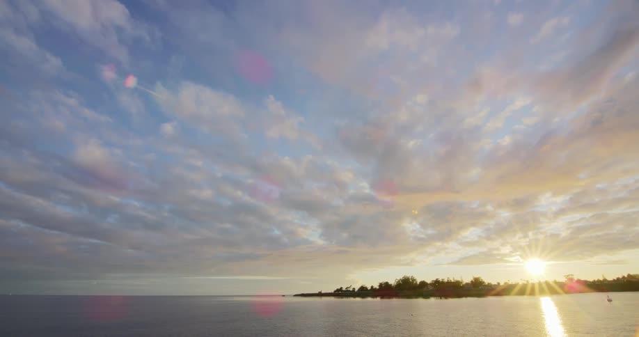 The sun starts to rise in the sky over the sea