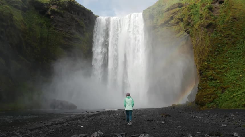 A person walks towards a waterfall