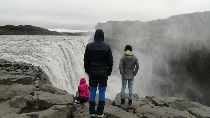 Three people are standing at the top of a waterfall watching
