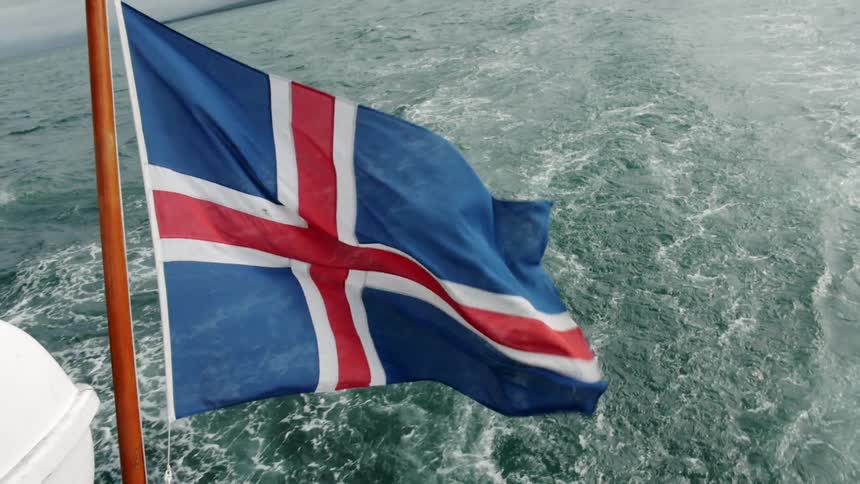 The Icelandic flag flies on the back on a boat in the ocean