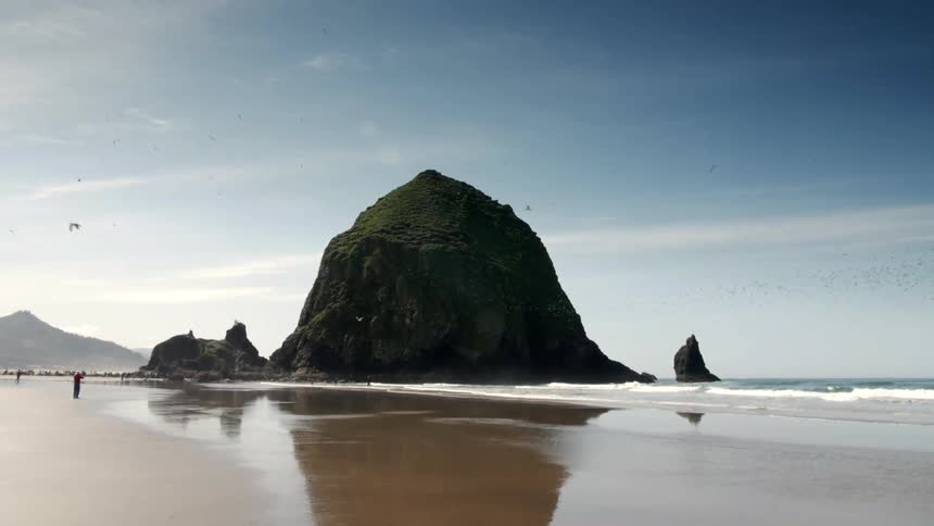 A large rock at the beach on a clear day