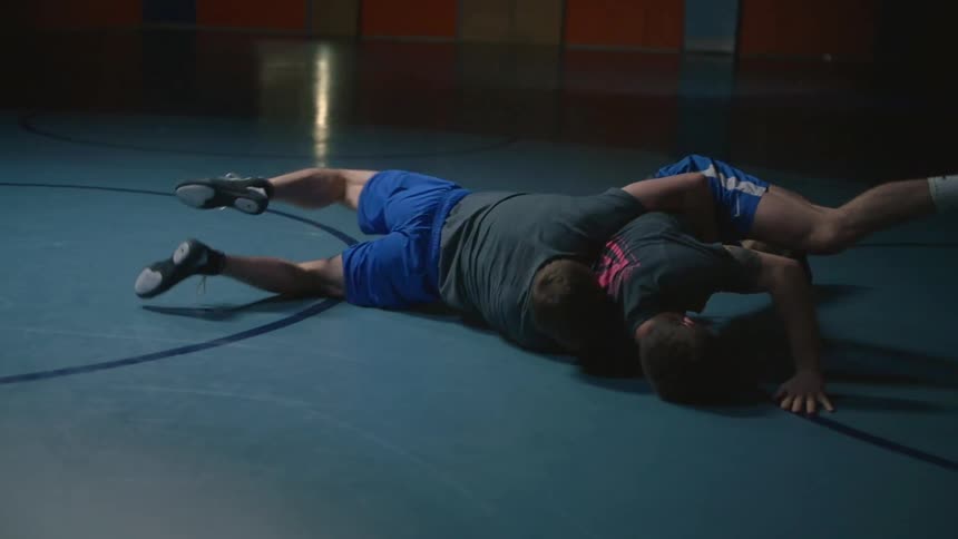 Two men wrestle in a gymnasium