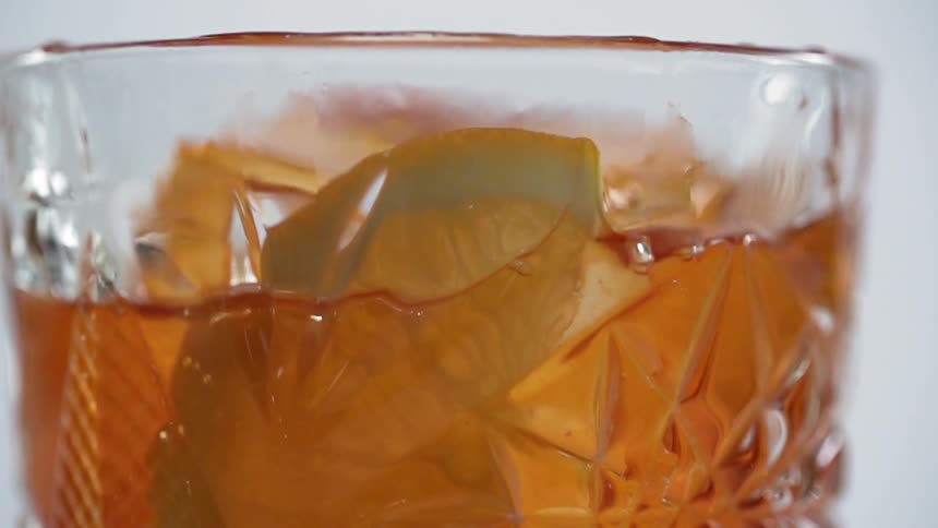 A lemon wedge is being dropped into a mixed drink
