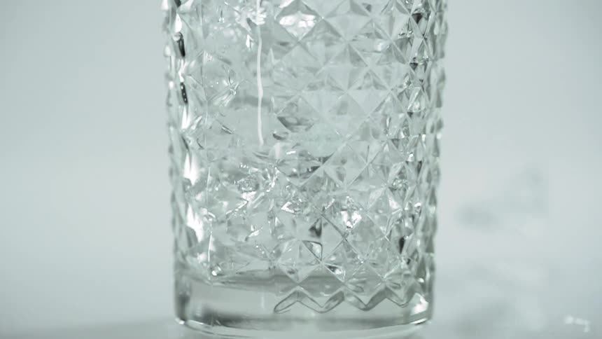 Ice being dropped in a cocktail glass in a studio